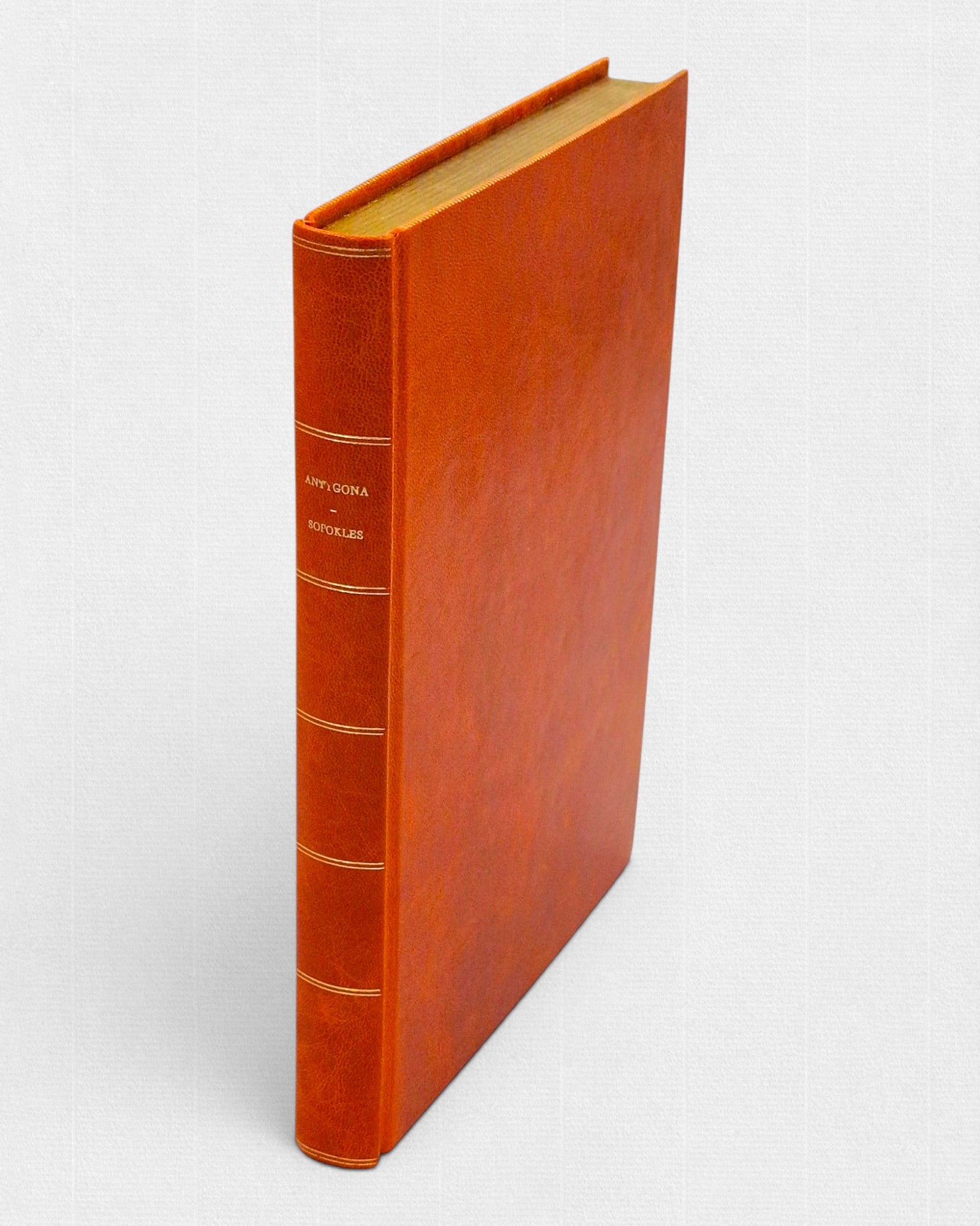 Antygona Sofoklesa – luksusowe wydanie w pełnej, ręcznie oprawionej skórze w kolorze pomarańczowym, ze złoconymi liniami i tytułem na grzbiecie.
