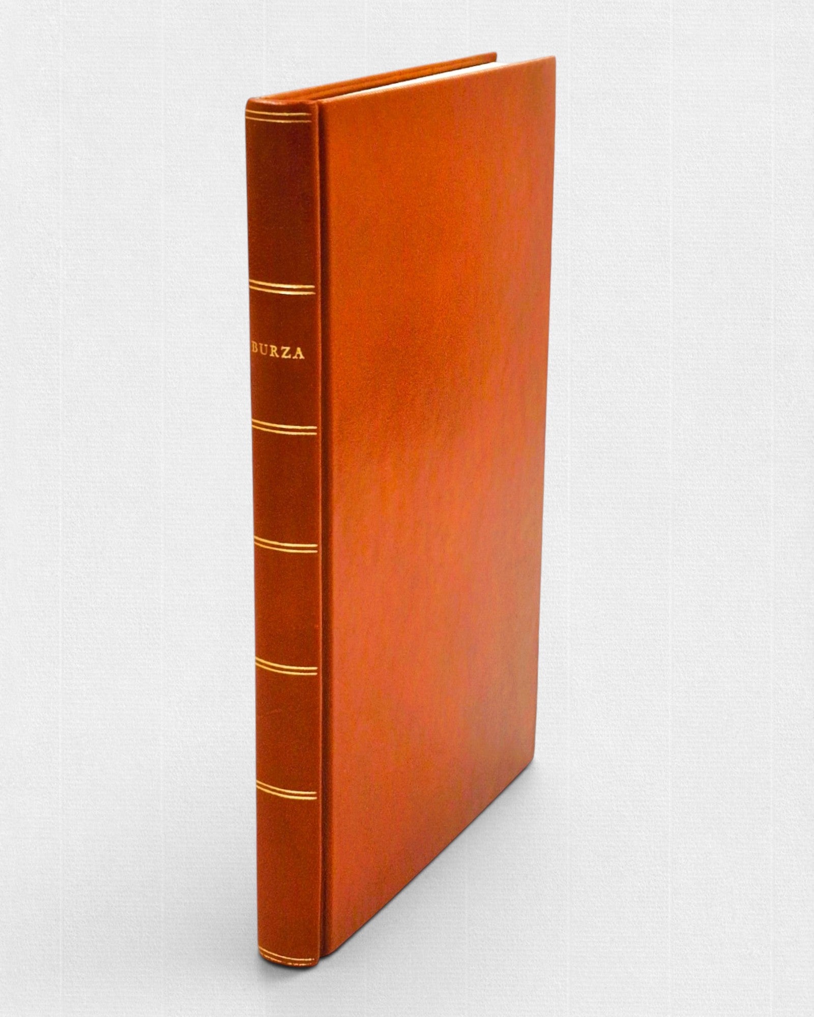 Luksusowe wydanie „Burzy” Williama Szekspira w minimalistycznej, ręcznie wykonanej oprawie skórzanej w odcieniu ciepłej czerwieni, z subtelnymi złoceniami na grzbiecie.