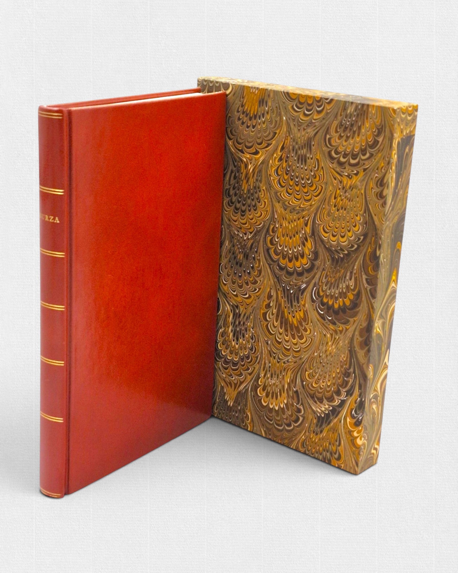 Luksusowe wydanie „Burzy” Williama Szekspira w ręcznej, czerwonej oprawie skórzanej, prezentowane wraz z ozdobnym etui w marmurkowym wzorze.