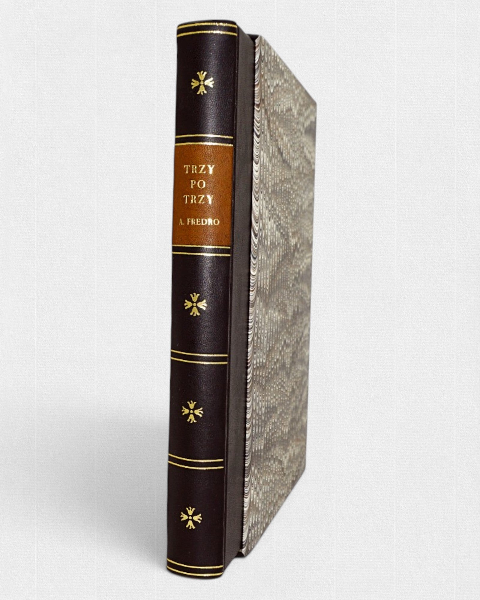 Książka „Trzy po trzy” Aleksandra Fredry w eleganckiej oprawie półskórkowej z marmurkowym etui, widok grzbietu